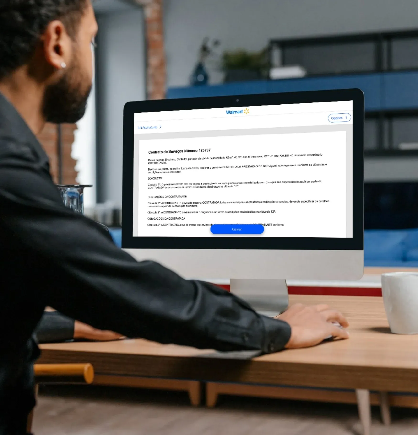 Homem em uma mesa olhando o contrato de prestação de serviços em um iMac, com o botão Assinar